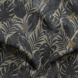 Detail of gently draped printed fabric in a tropical palm frond pattern in muted steel blue scattered with small tan lizards. 