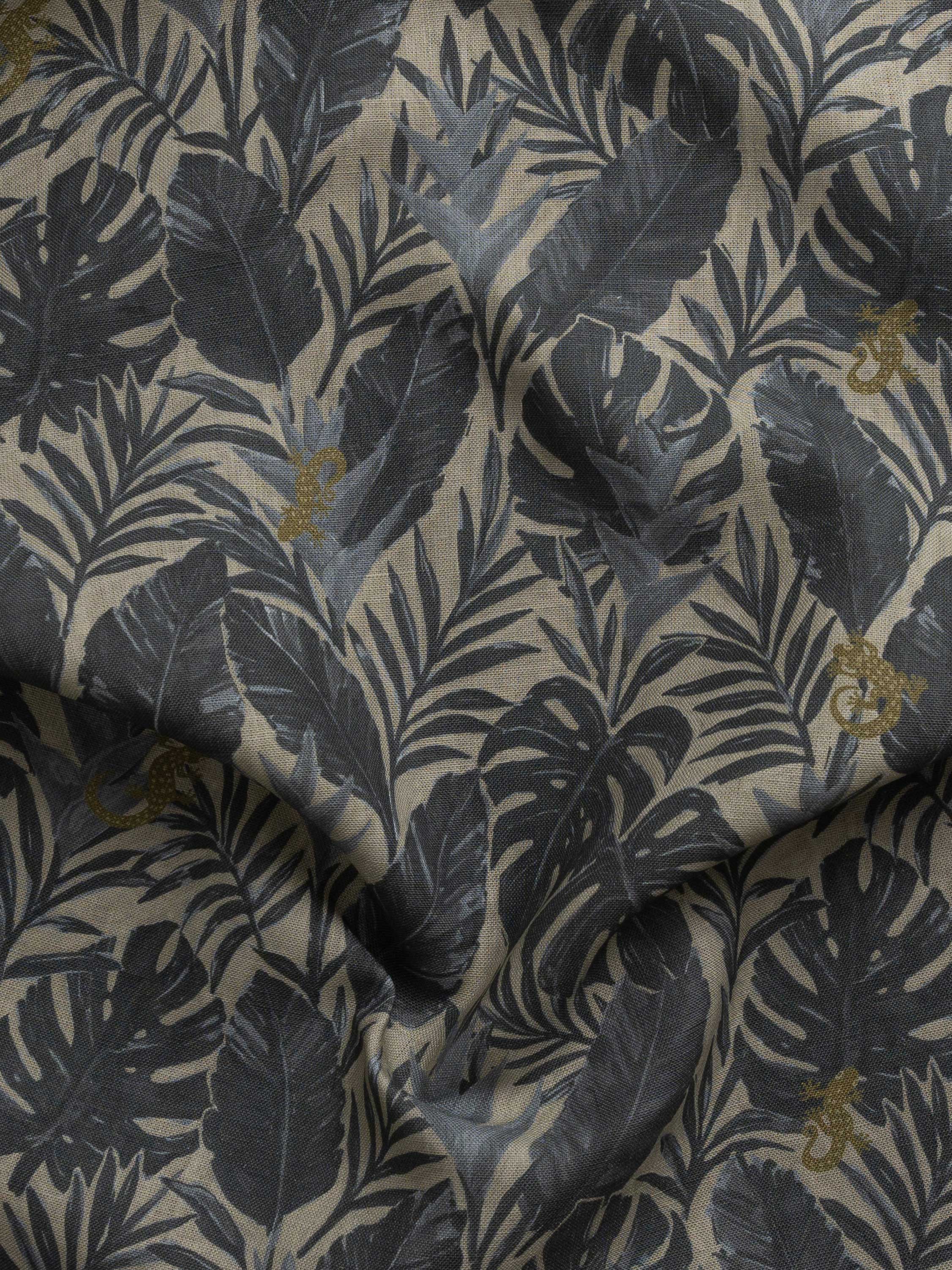 Detail of gently draped printed fabric in a tropical palm frond pattern in muted steel blue scattered with small tan lizards. 