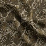 Detail of gently draped printed fabric in a tropical palm frond pattern in muted brown  scattered with small grey-green lizards. 