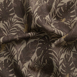 Detail of gently draped printed fabric in a tropical palm frond pattern in tonal brown scattered with small tan lizards. 