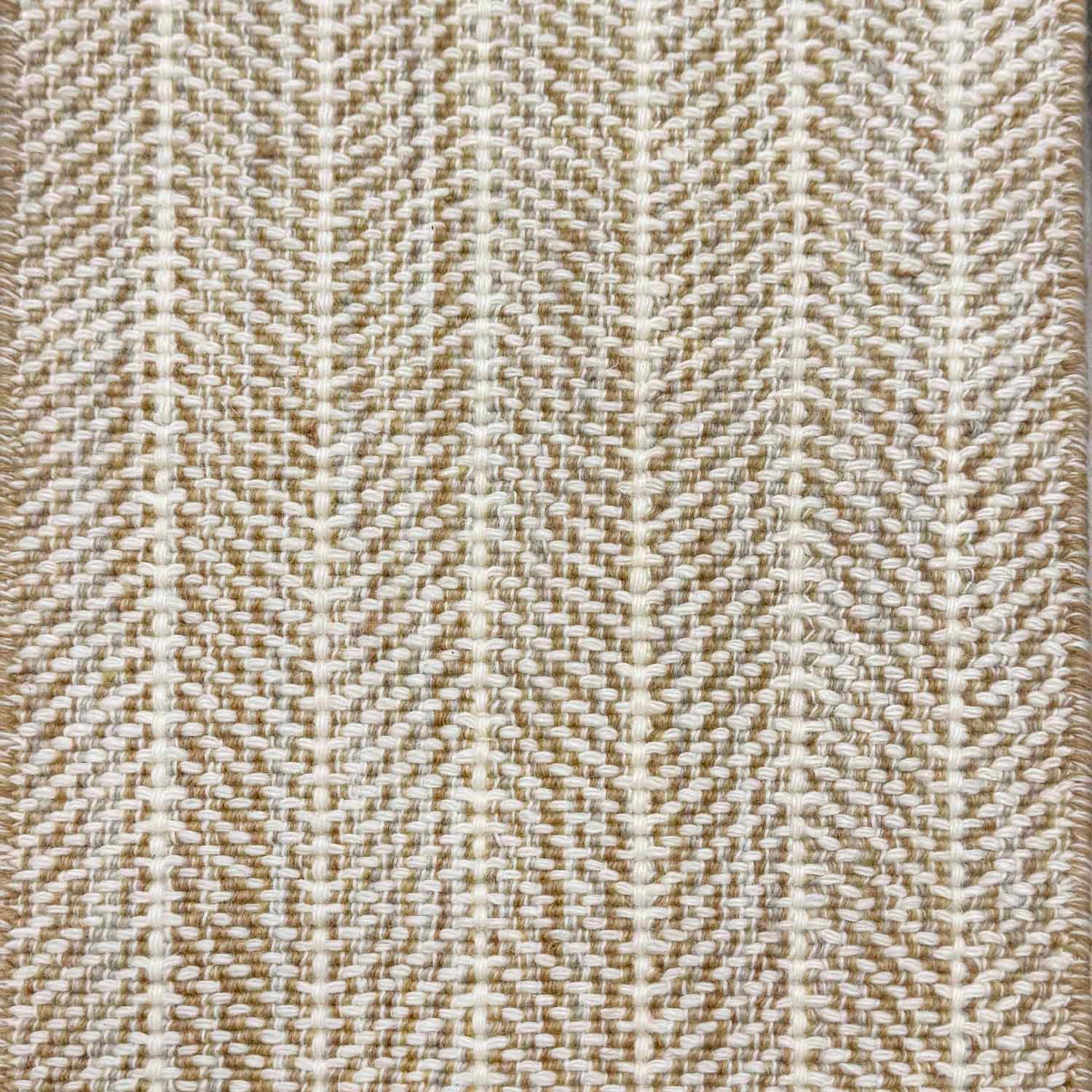 Close up of broadloom carpet with striated herringbone weave in white with accents of tan and brown.