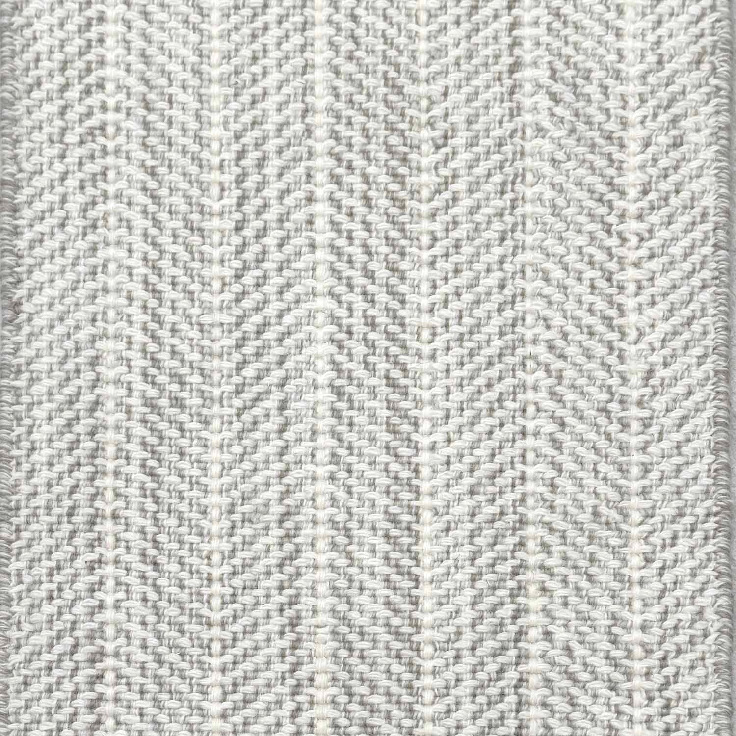 Close up of broadloom carpet with striated herringbone weave in white with accents of light grey.