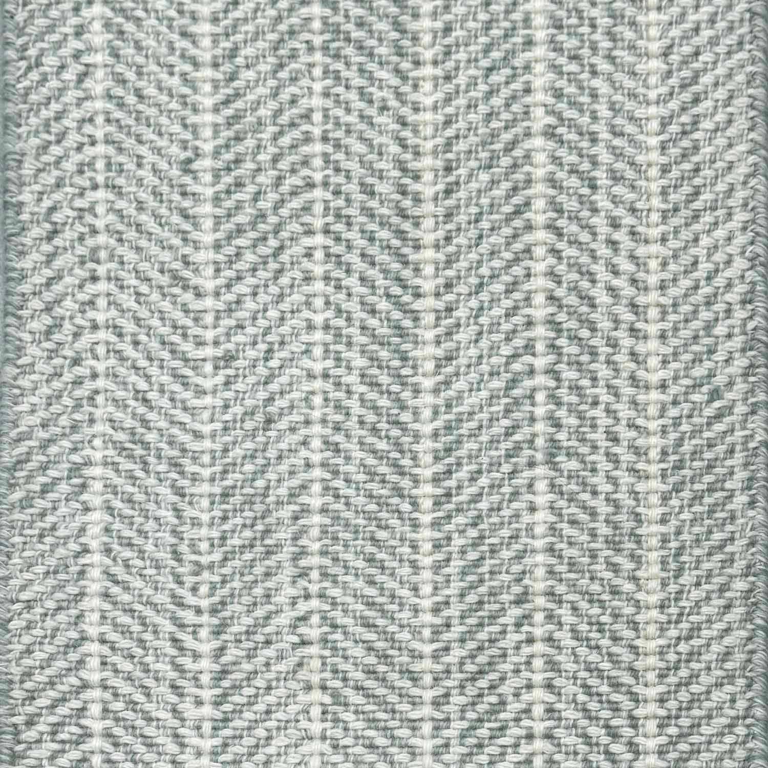 Close up of broadloom carpet with striated herringbone weave in white with accents of slate blue.