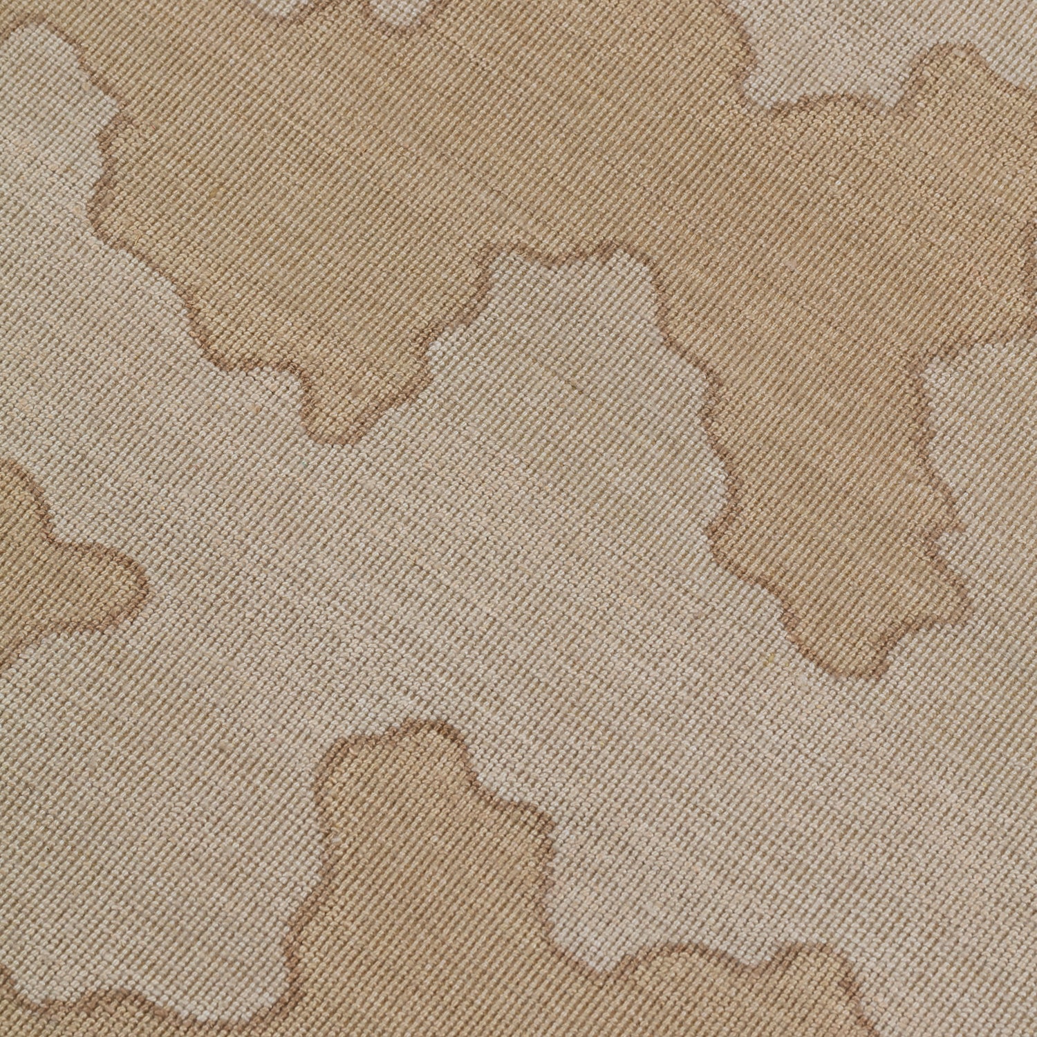 Detail of a handwoven rug in an abstract coral design in tonal shades of tan and taupe. 