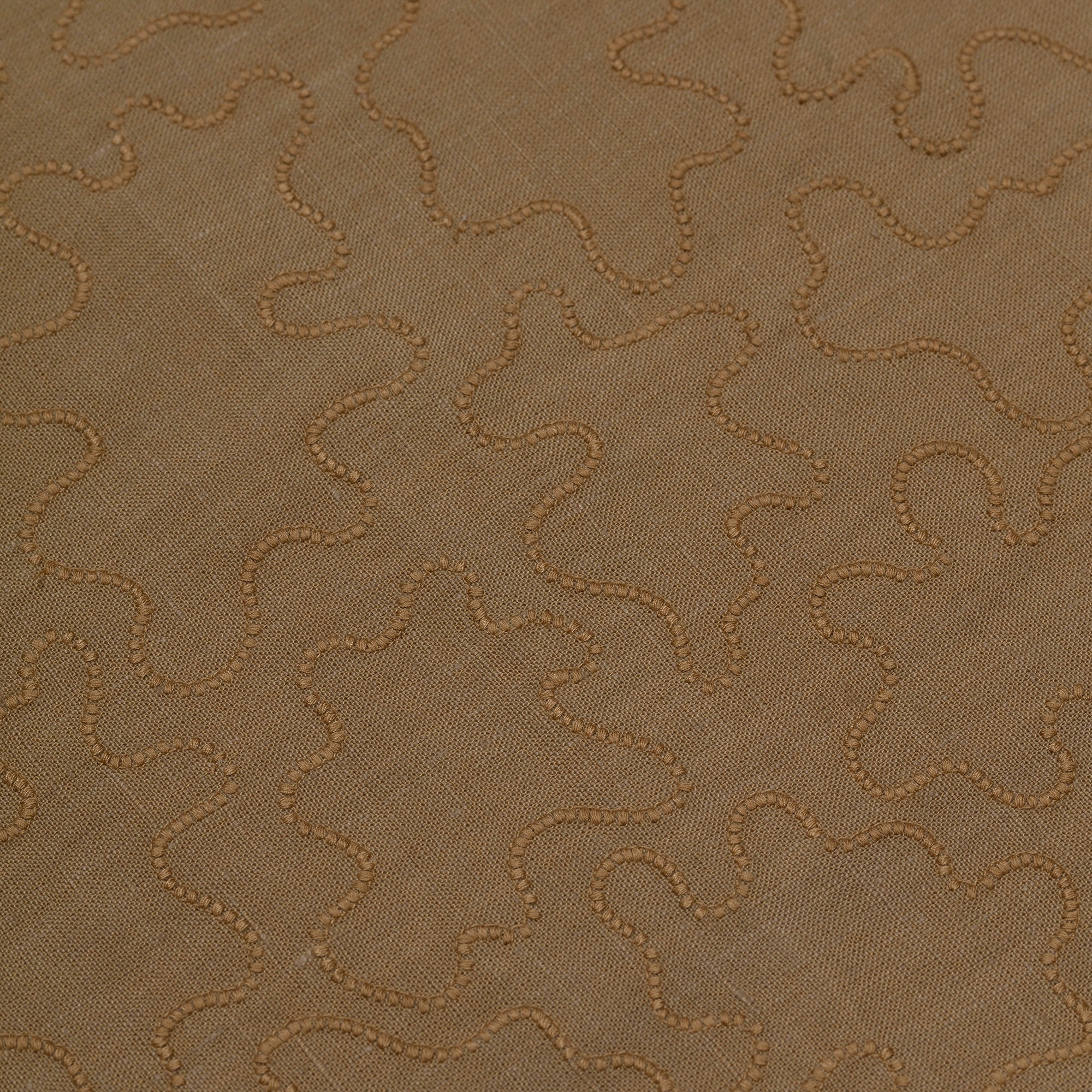 Detail of fabric with an abstract embroidered pattern in brown on a brown field.