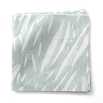 Stacked fabric swatches in an abstract leaf pattern in white on a pale aqua watercolor field.