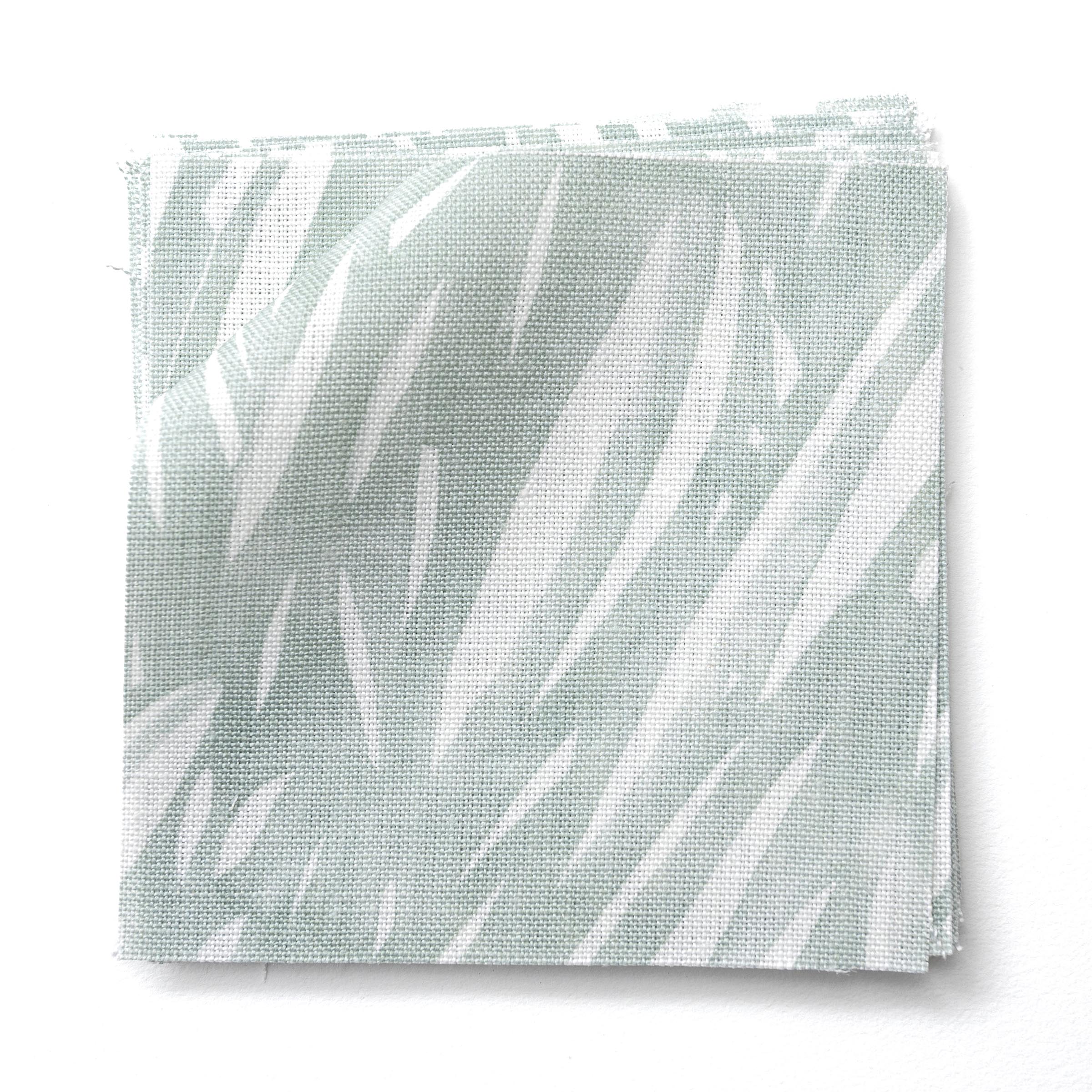 Stacked fabric swatches in an abstract leaf pattern in white on a pale aqua watercolor field.