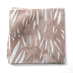 Fabric swatches in an abstract leaf pattern in white on a warm brown watercolor field.