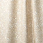 Draped linen in  an abstract leaf pattern in white on a pale yellow watercolor field.