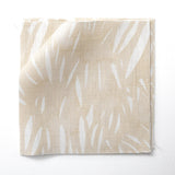 Fabric swatches in an abstract leaf pattern in white on a pale yellow watercolor field.