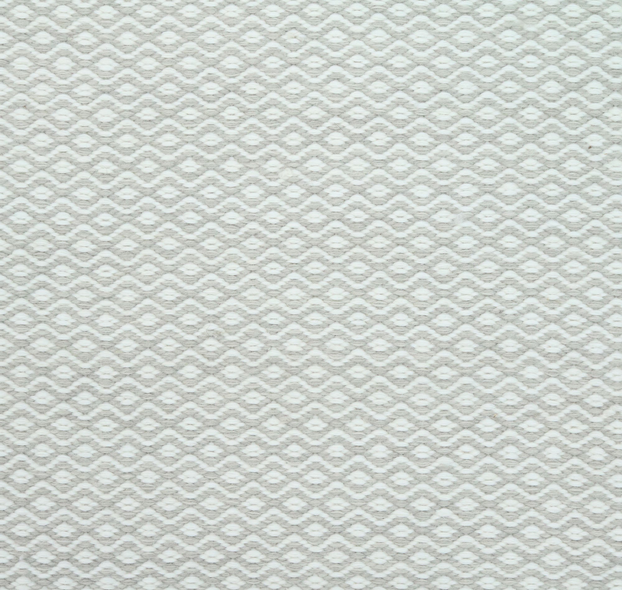 Flatweave rug in a small scale zigzag dot stripe in cream on a pale ecru field.