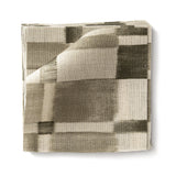 Stacked swatches of fabric in a large-scale checked pattern in shades of olive green and cream. 