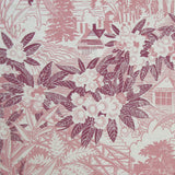 Detail of fabric in an intricate botanical, bridge and house print in pink and maroon on a cream field.