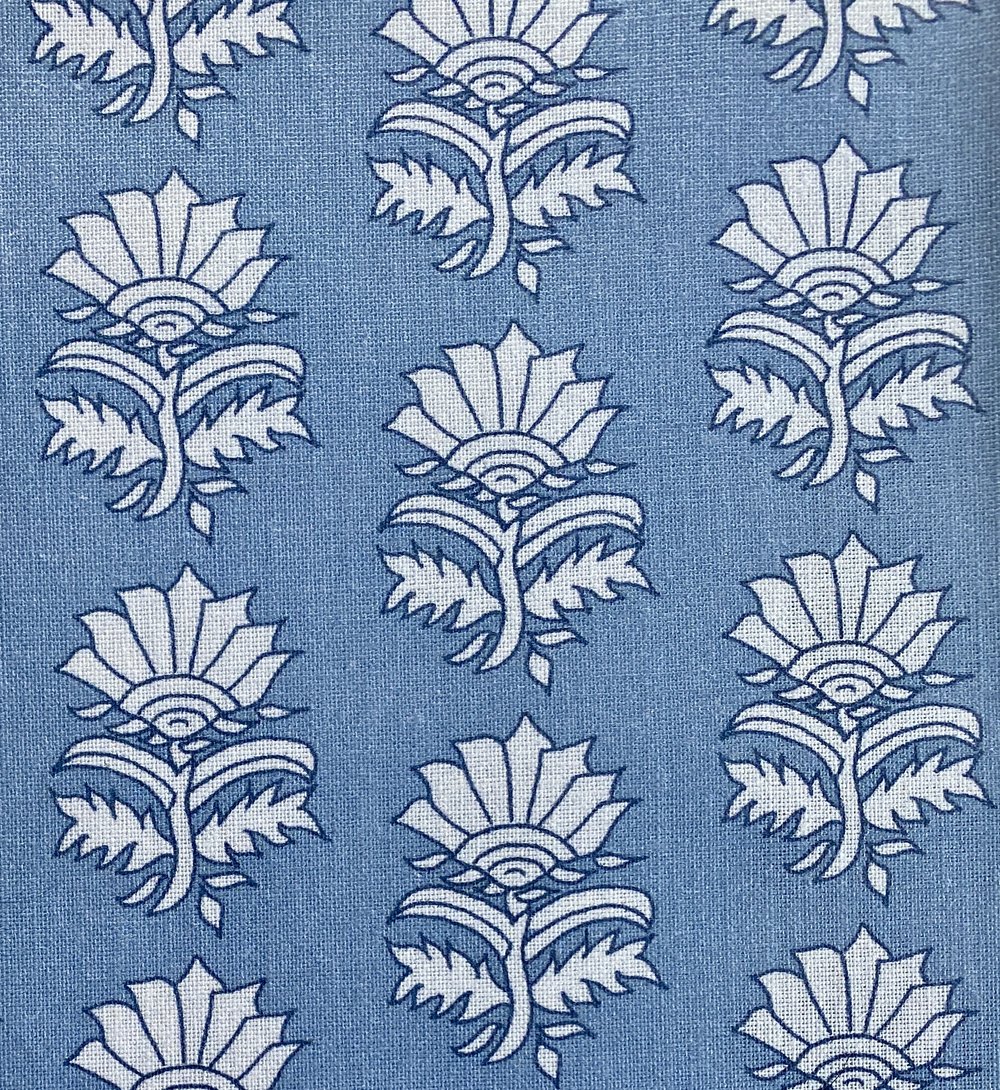 Detail of fabric in a repeating thistle print in navy and light blue on a blue field.