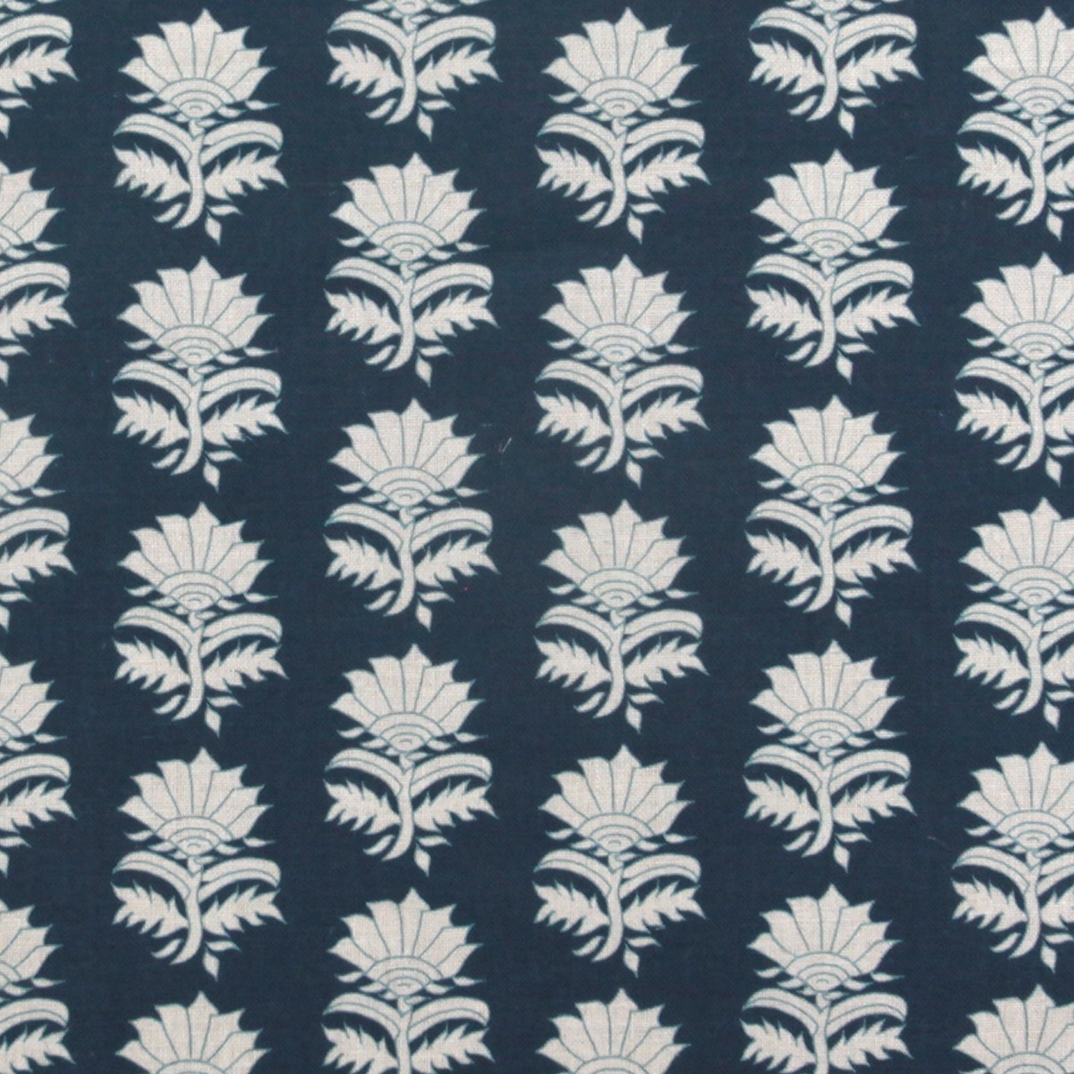 Detail of fabric in a repeating thistle print in white and blue on a navy field.
