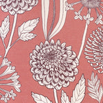 Detail of fabric in a large-scale floral print in purple and white on a light pink field.