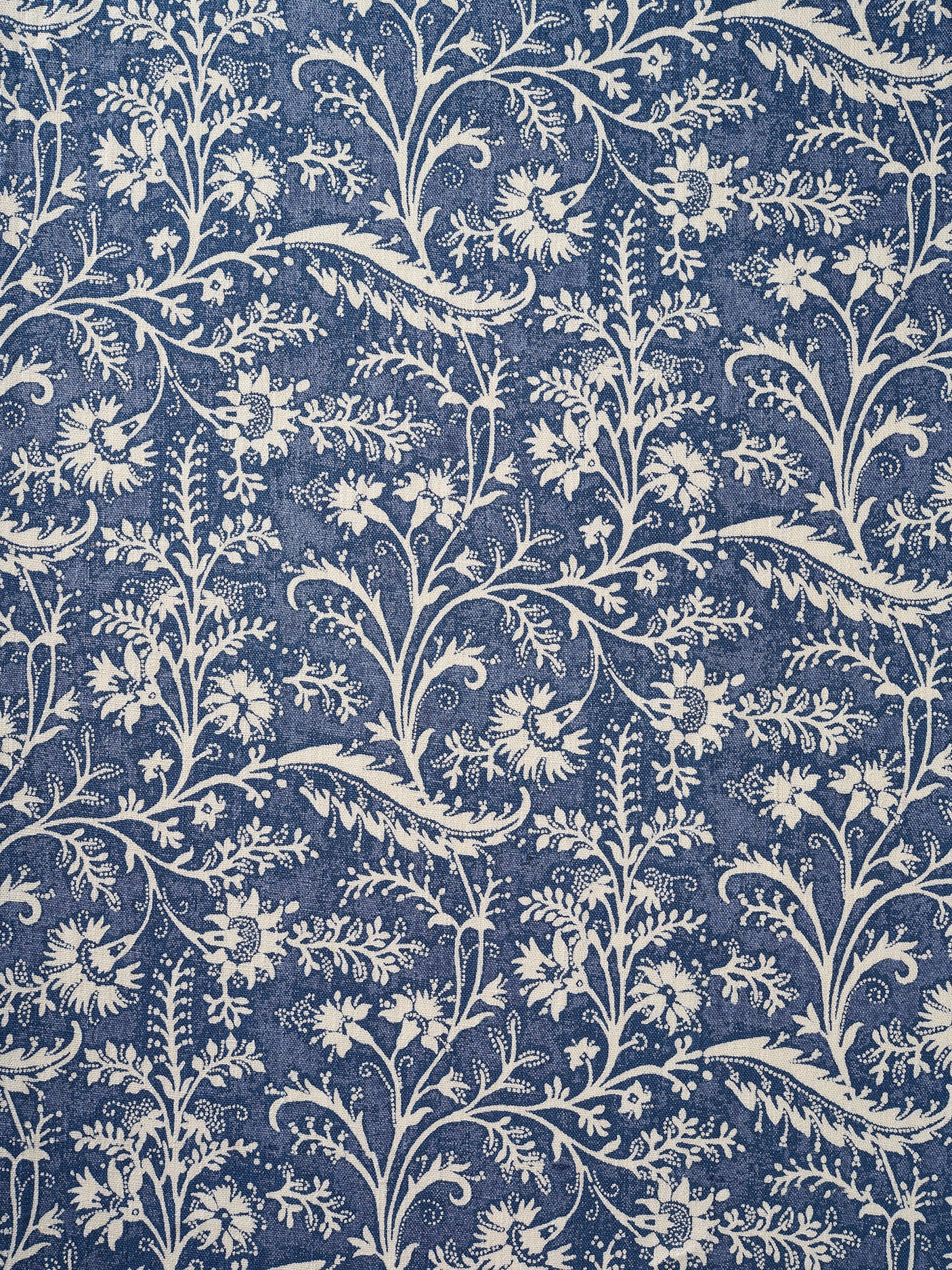 A close-up of a repeating floral and vine pattern in muted denim blue and off-white.