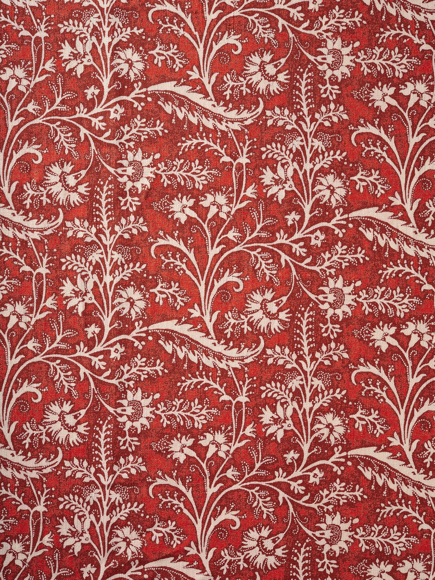 A close-up of a repeating floral and vine pattern in bright red and off-white.
