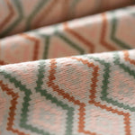 Close-up of patterned fabric with geometric design in brown, pink, and green.