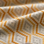 Close-up of fabric with a geometric pattern in yellow beige, and white.