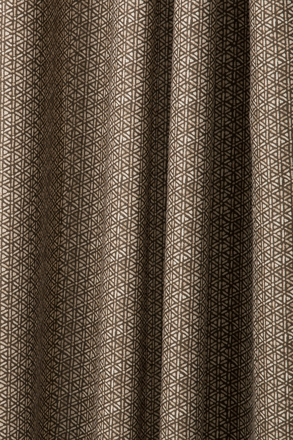 Draped printed fabric in a detailed geometric pattern in white on a dark brown field.