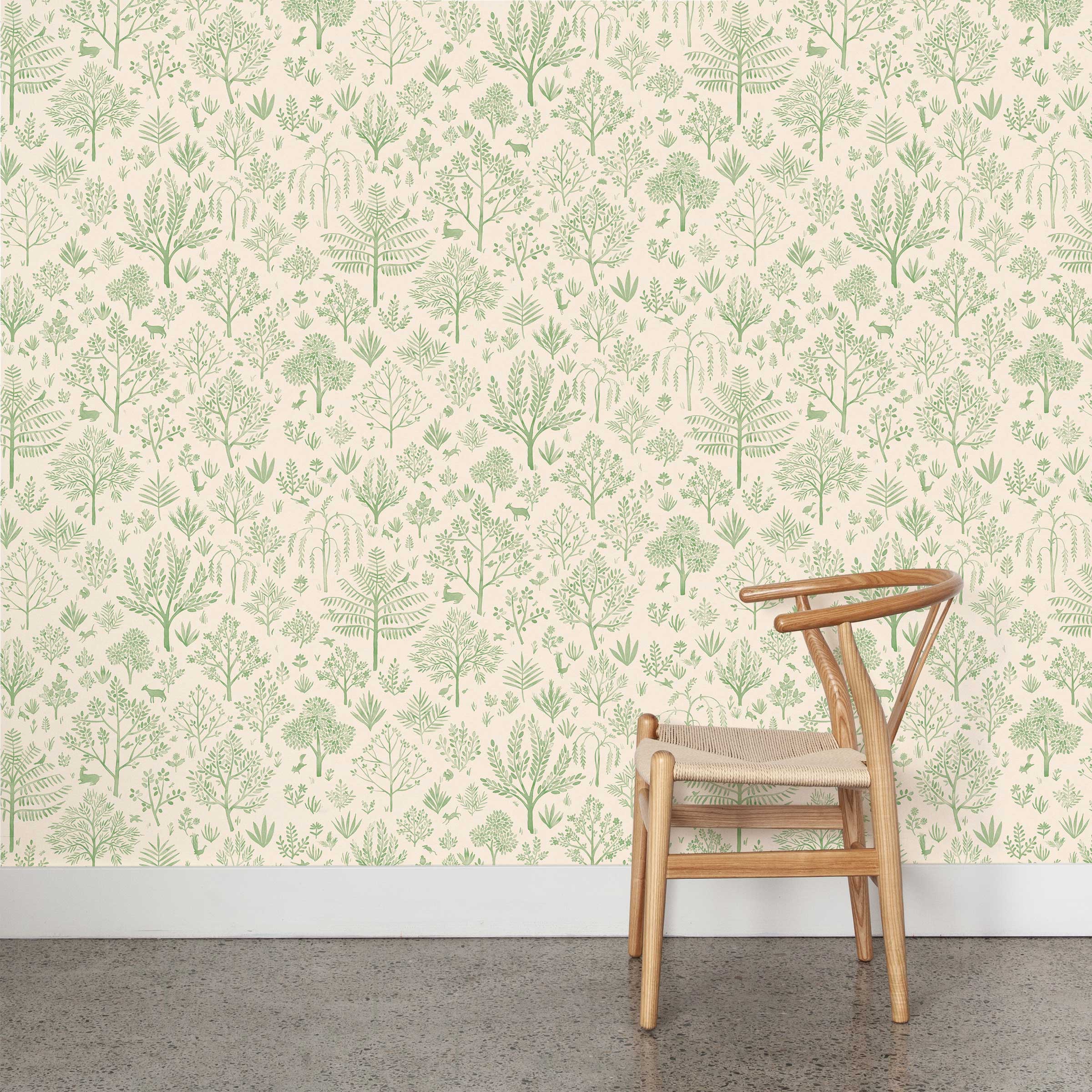 A wooden chair stands in front of a wall papered in a playful animal and tree print in green on a cream field.