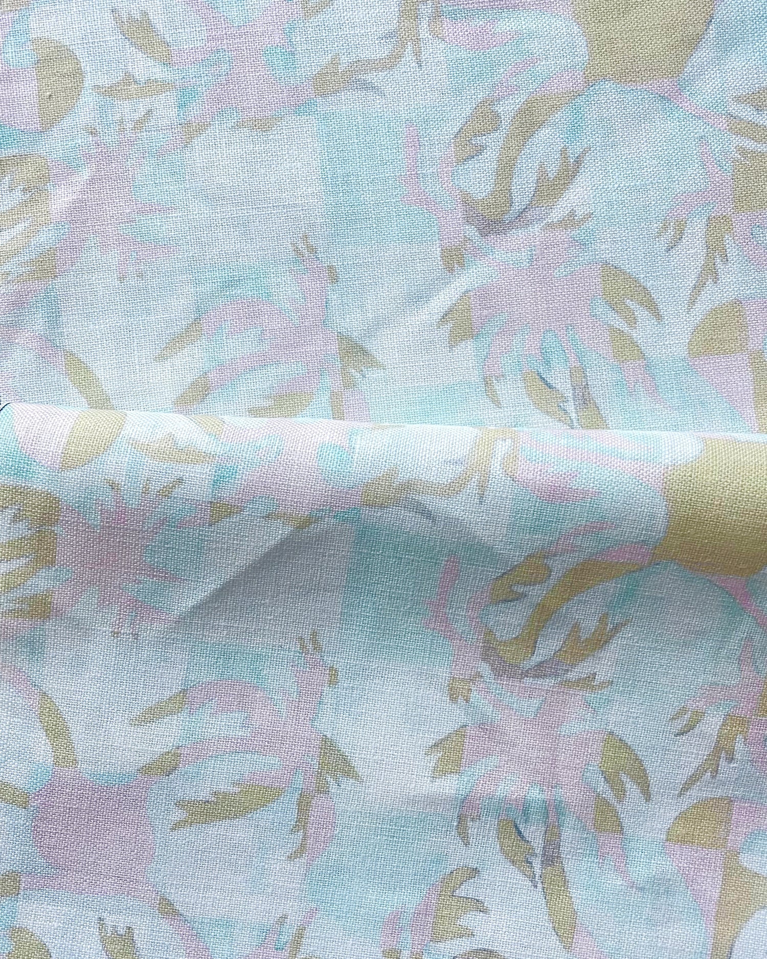 Draped fabric with painterly tropical checkerboard design in aqua blue, pink and tan.