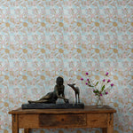 Wooden table with decorative items against a blue and ink tropical check patterned wallpaper.