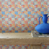 Colorful geometric tropical patterned wallpaper with a blue vase on a wooden surface.