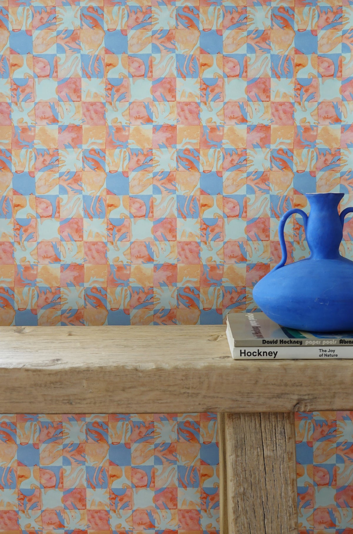 Colorful geometric patterned wallpaper with a blue vase on a wooden surface.