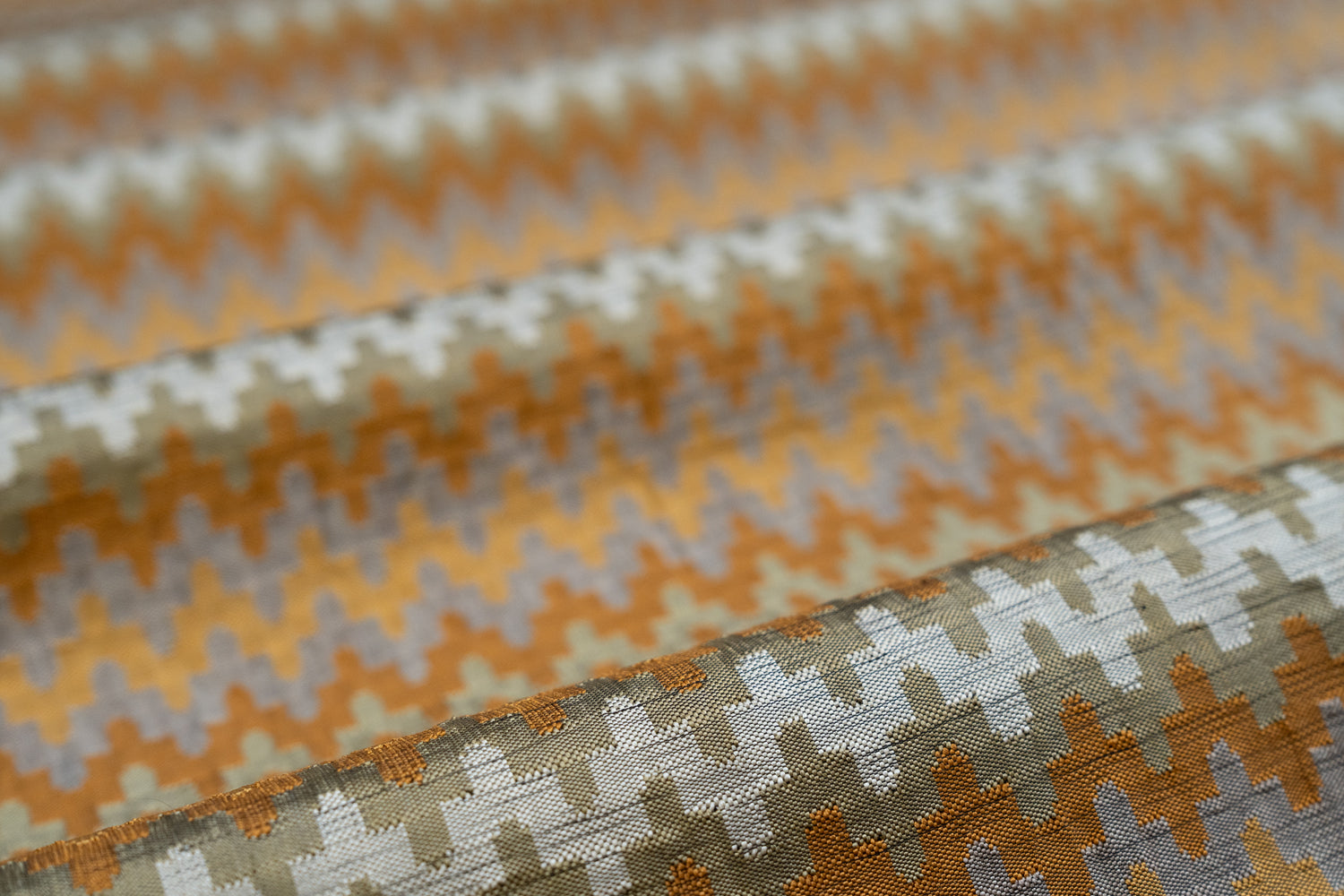Close-up of fabric with a zigzag pattern in orange, beige, and brown.