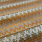 Close-up of fabric with a zigzag pattern in orange, beige, and brown.