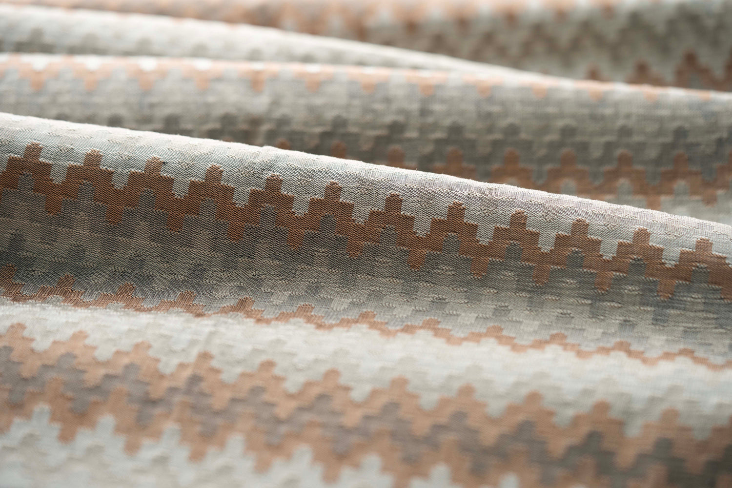 Close up of folded handwoven silk fabric with zigzag stripes in neutral colors. 