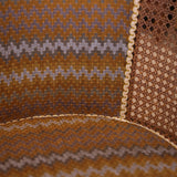 Textured fabric with wavy pattern in brown, beige, and purple on a brown background.