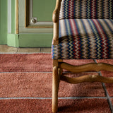 Chair with patterned fabric on a red carpet in a room with green walls.