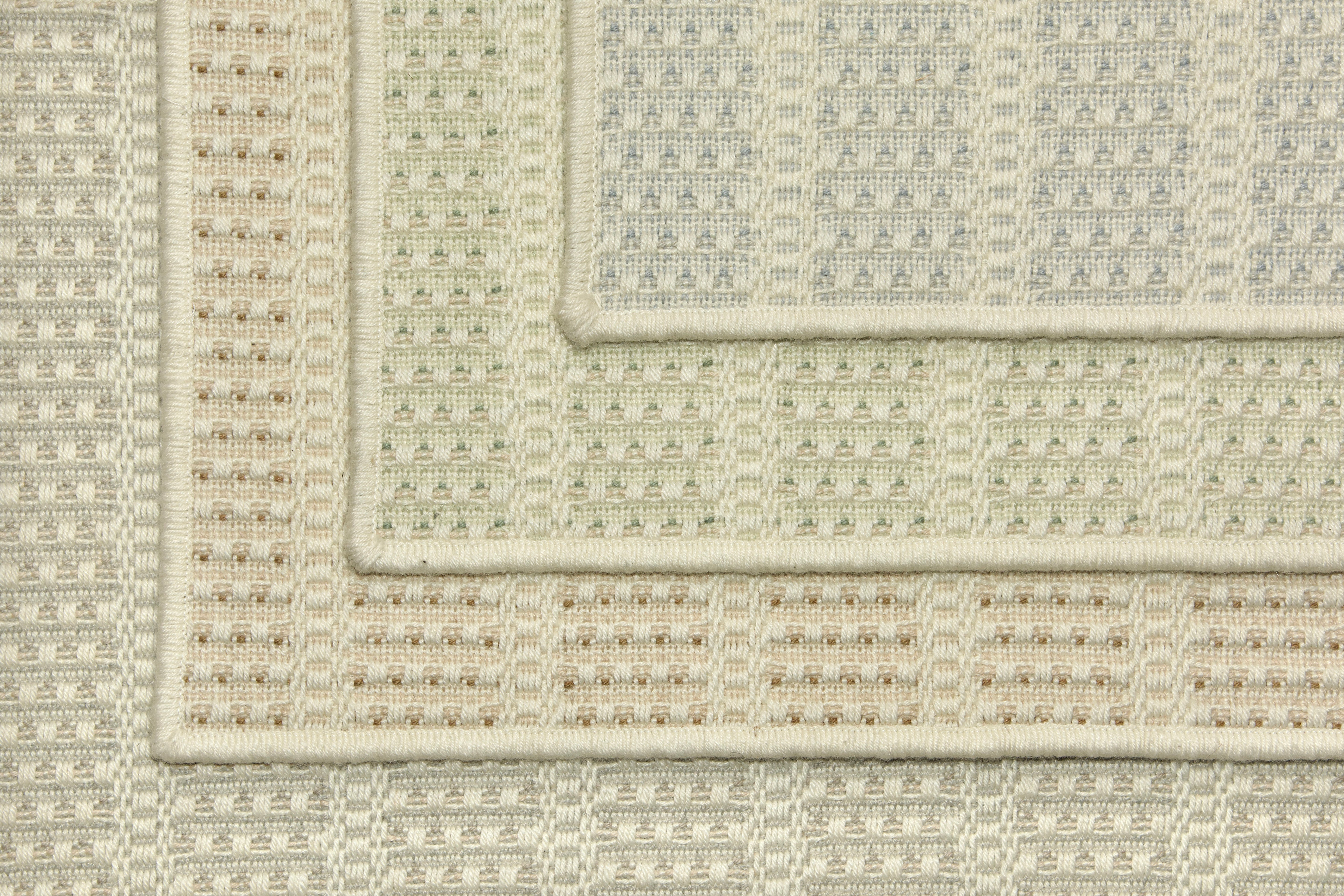 Stack of four broadloom carpet samples with textured stripe design in a palette of cream and pastel hues.