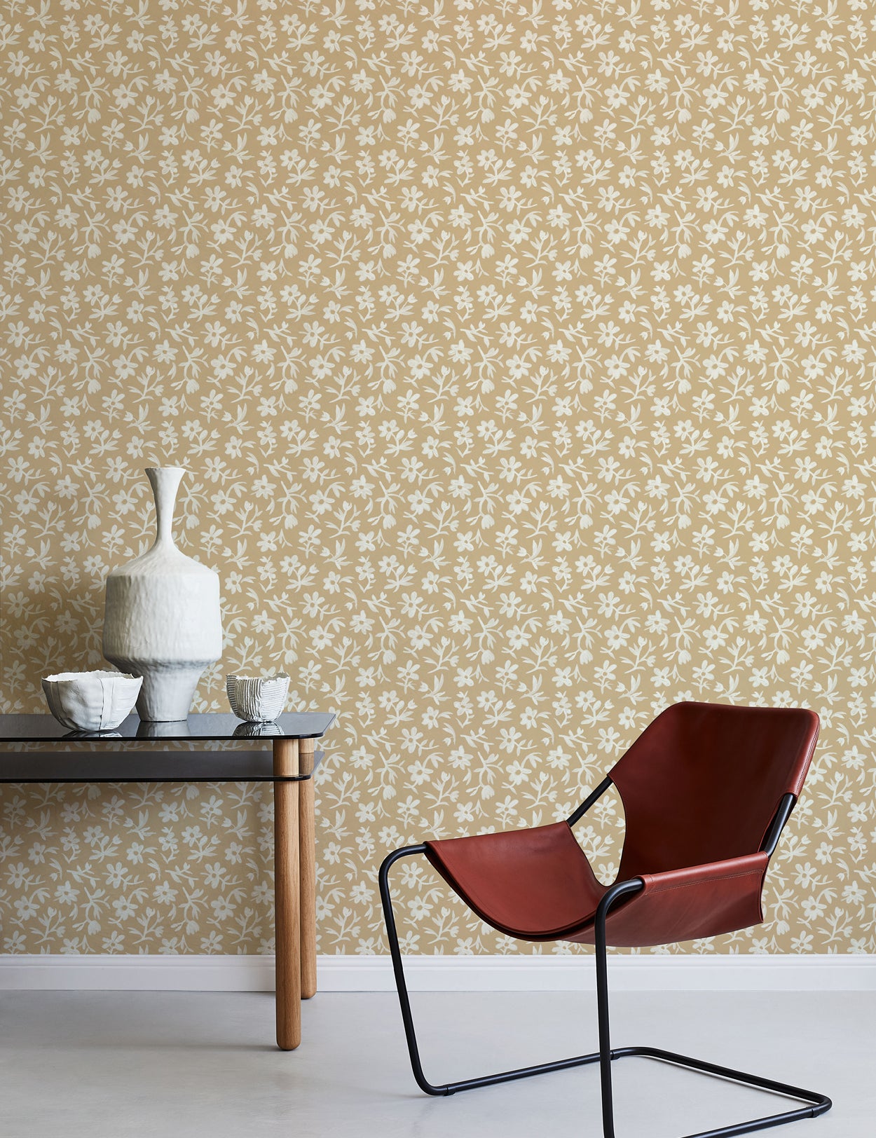 Modern chair and table against a white and tan floral wallpapered wall.