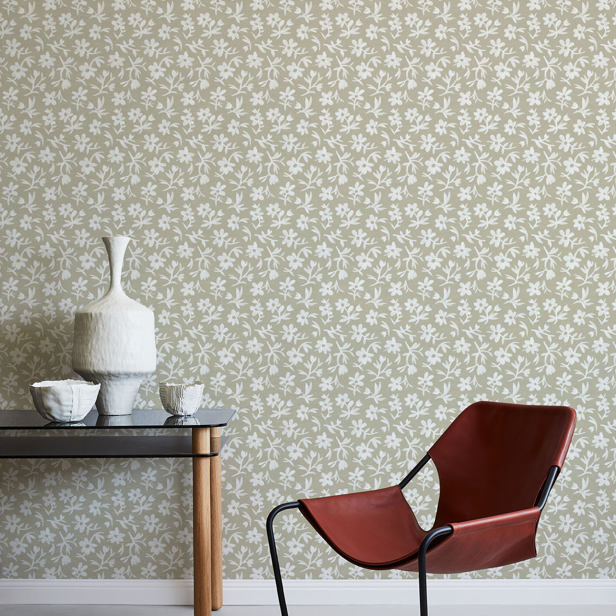 Modern chair against a floral wallpapered wall with a small table and decorative items.