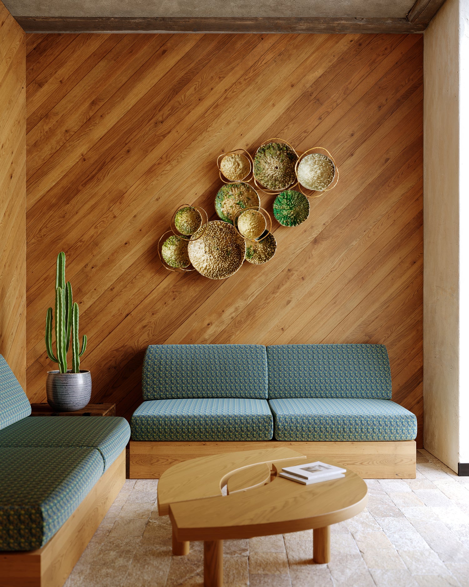 Modern living room with wooden walls, teal sofa, and decorative wall art.