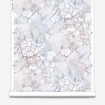 Partially unrolled wallpaper yardage in a watercolor textural print in shades of white, purple and gray.