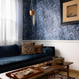 A maximalist living room tableau with walls papered in a watercolor textural print in blue, navy and black.