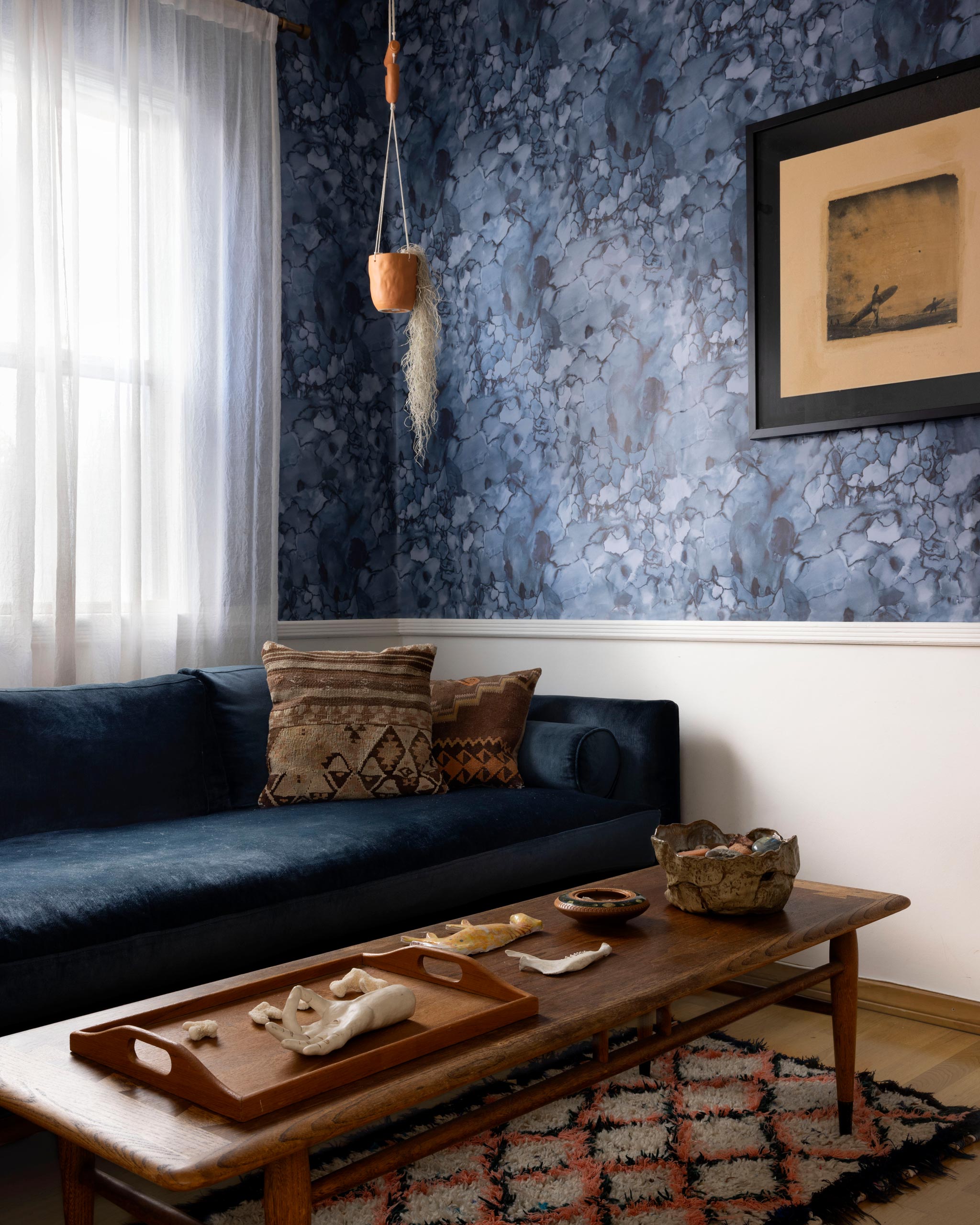 A maximalist living room tableau with walls papered in a watercolor textural print in blue, navy and black.