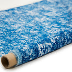 Partially unrolled fabric in an organic crumpled texture in navy on a cream field.