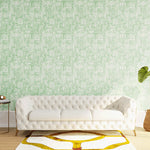 Styled living room tableau with a wall papered in an organic textural print in light green on a white field.