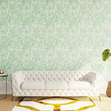 Styled living room tableau with a wall papered in an organic textural print in light green on a white field.