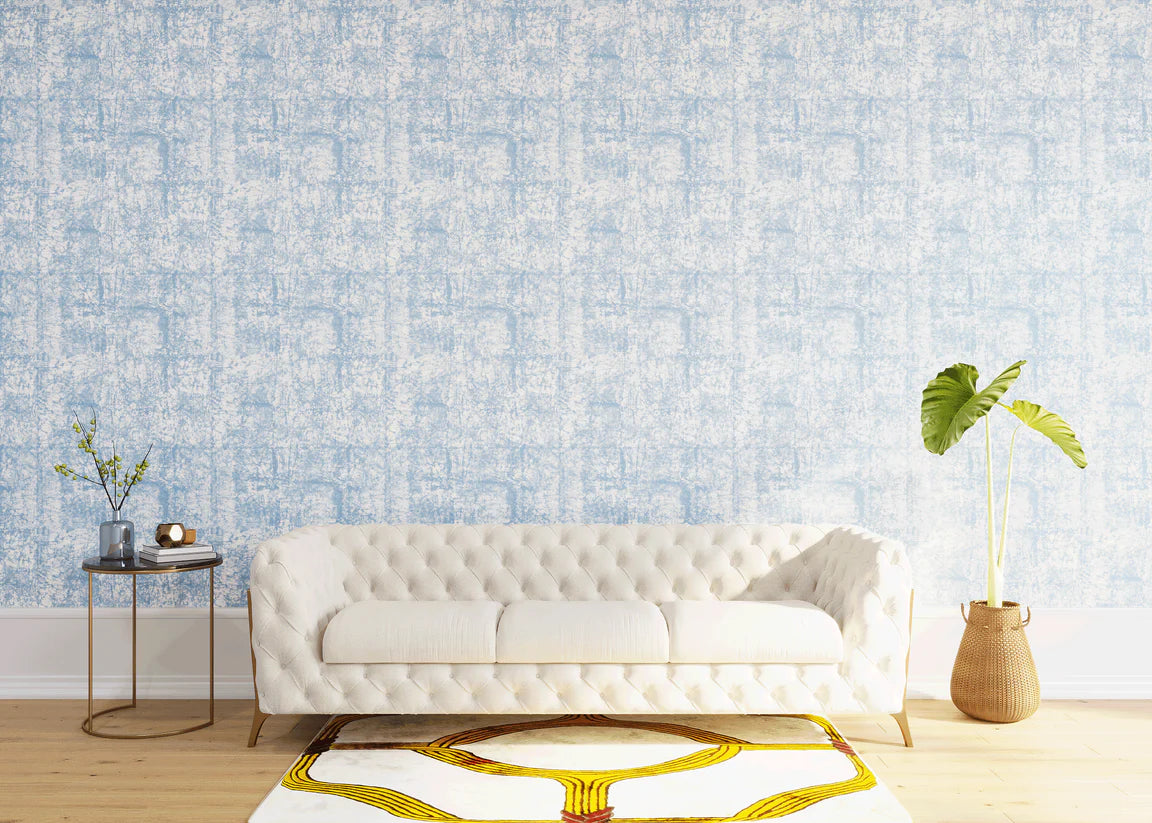 Styled living room tableau with a wall papered in an organic textural print in light blue on a white field.