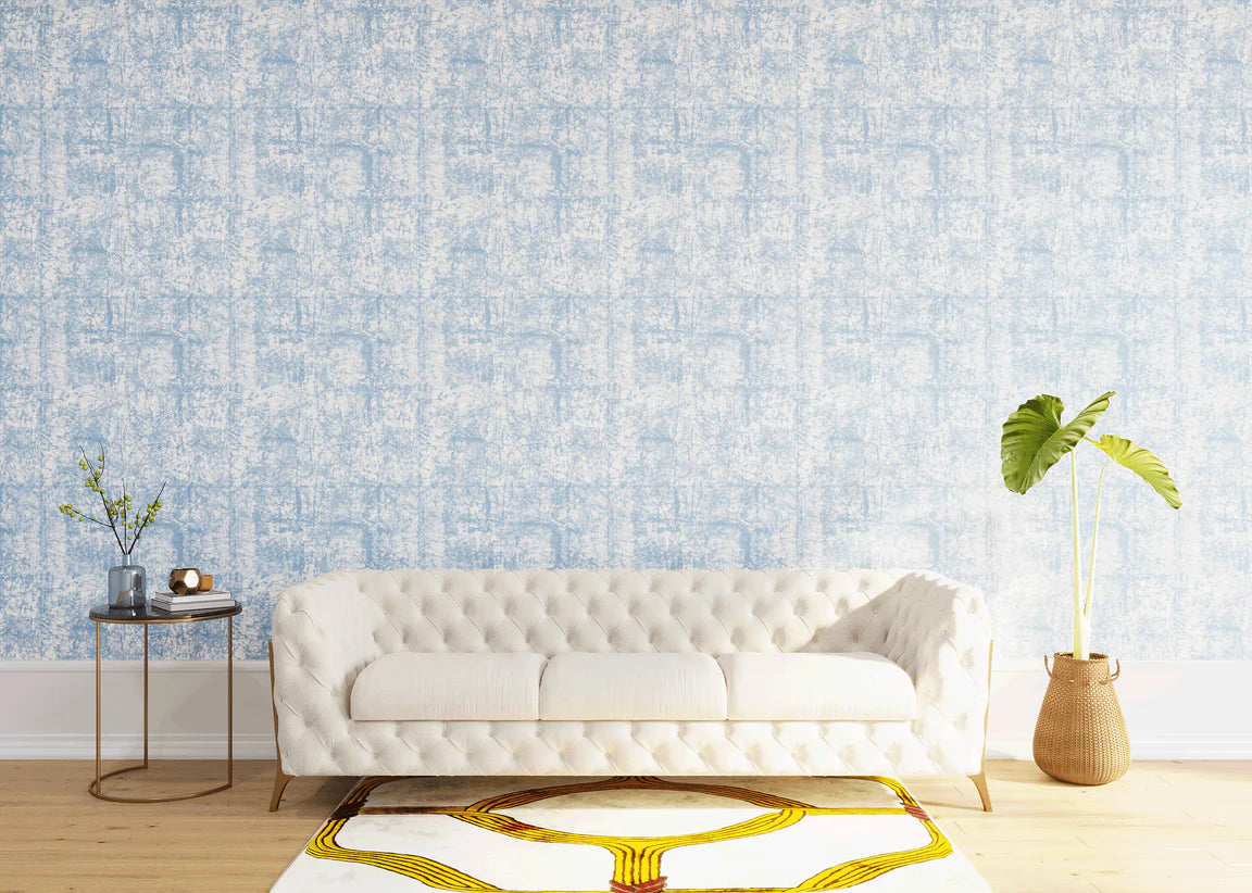 Styled living room tableau with a wall papered in an organic textural print in light blue on a white field.