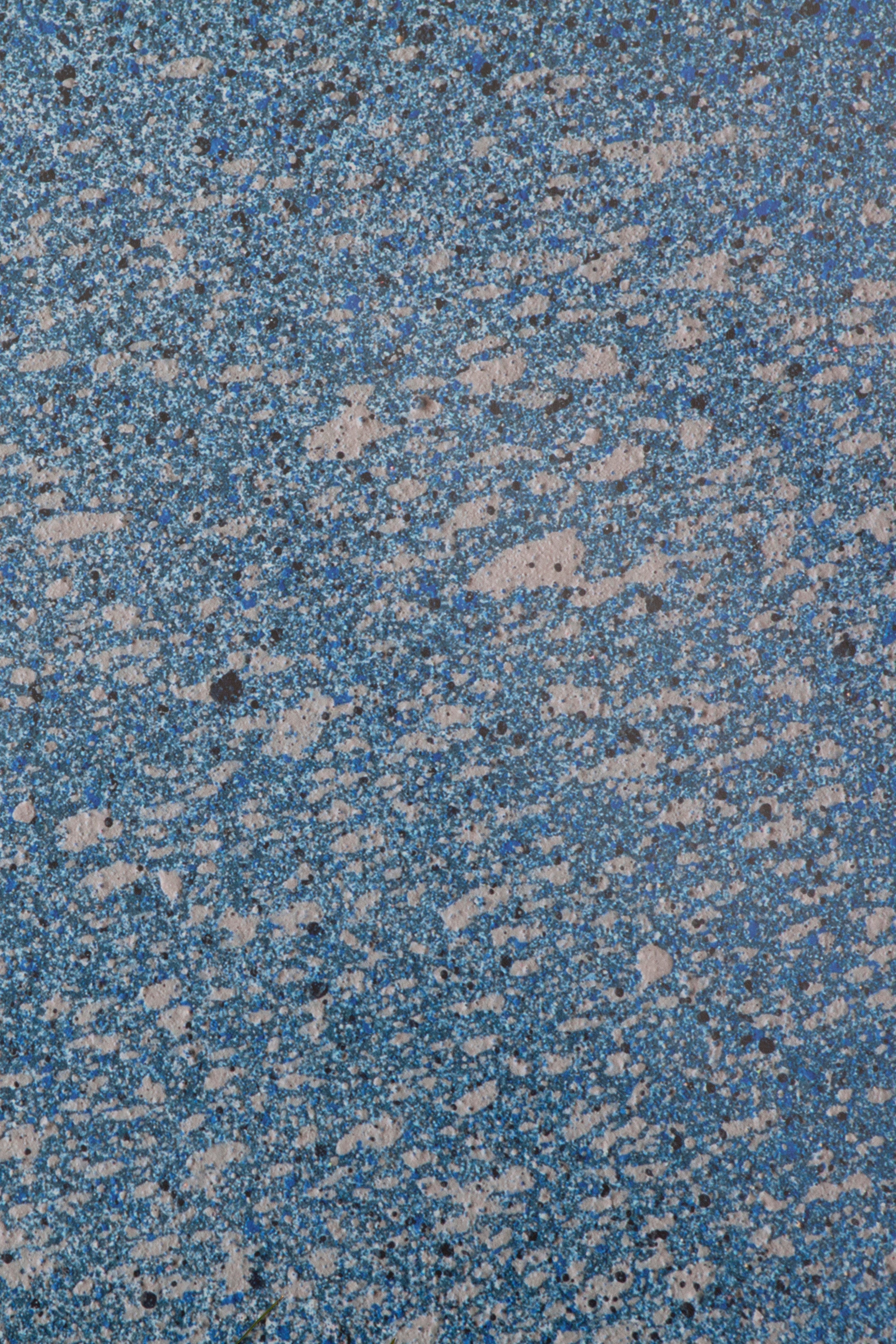 Close up of paint splatters in pink and navy on a blue field.