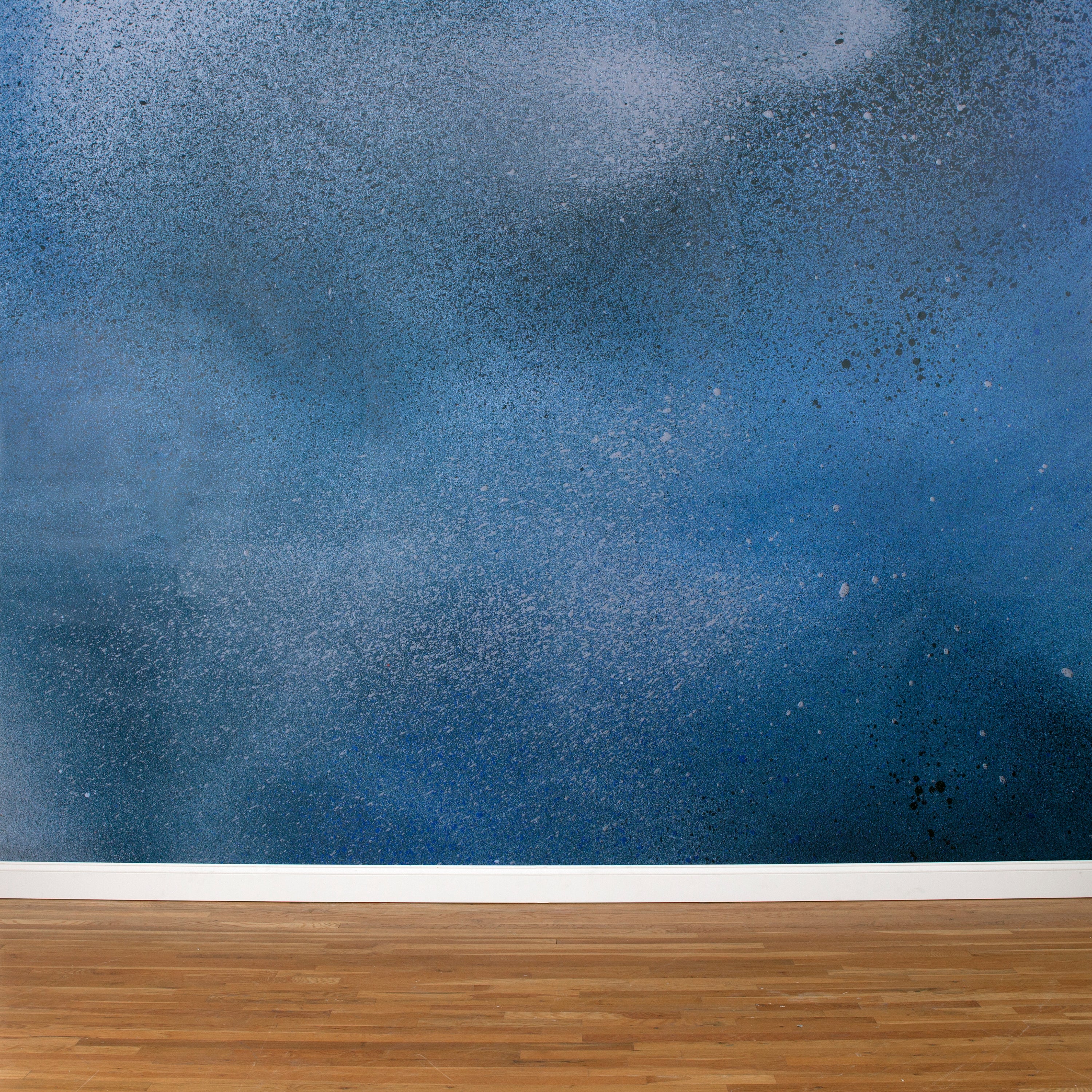 A wall mural in an abstract ombré paint splatter print in shades of blue, white and navy.