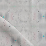Detail of draped fabric yardage in a repeating ink blot print in shades of gray with turquoise and pink accents.